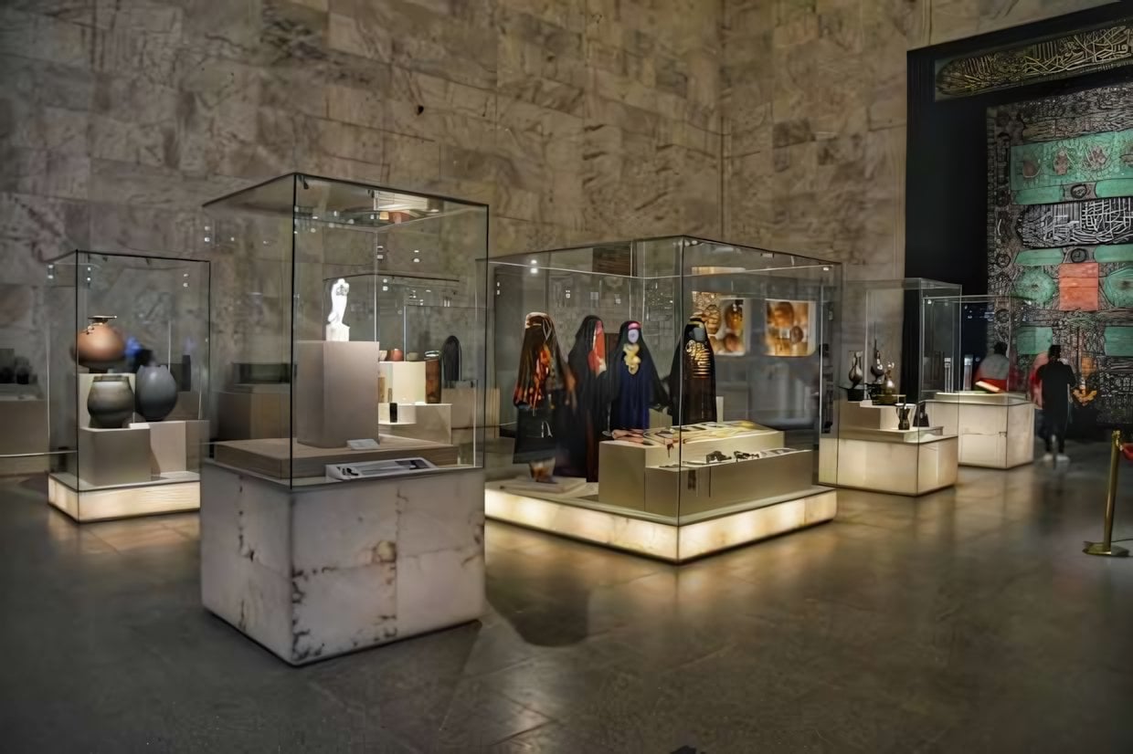 Salle d'exposition intérieure du Grand Musée Égyptien, présentant des objets culturels et des vêtements dans des vitrines