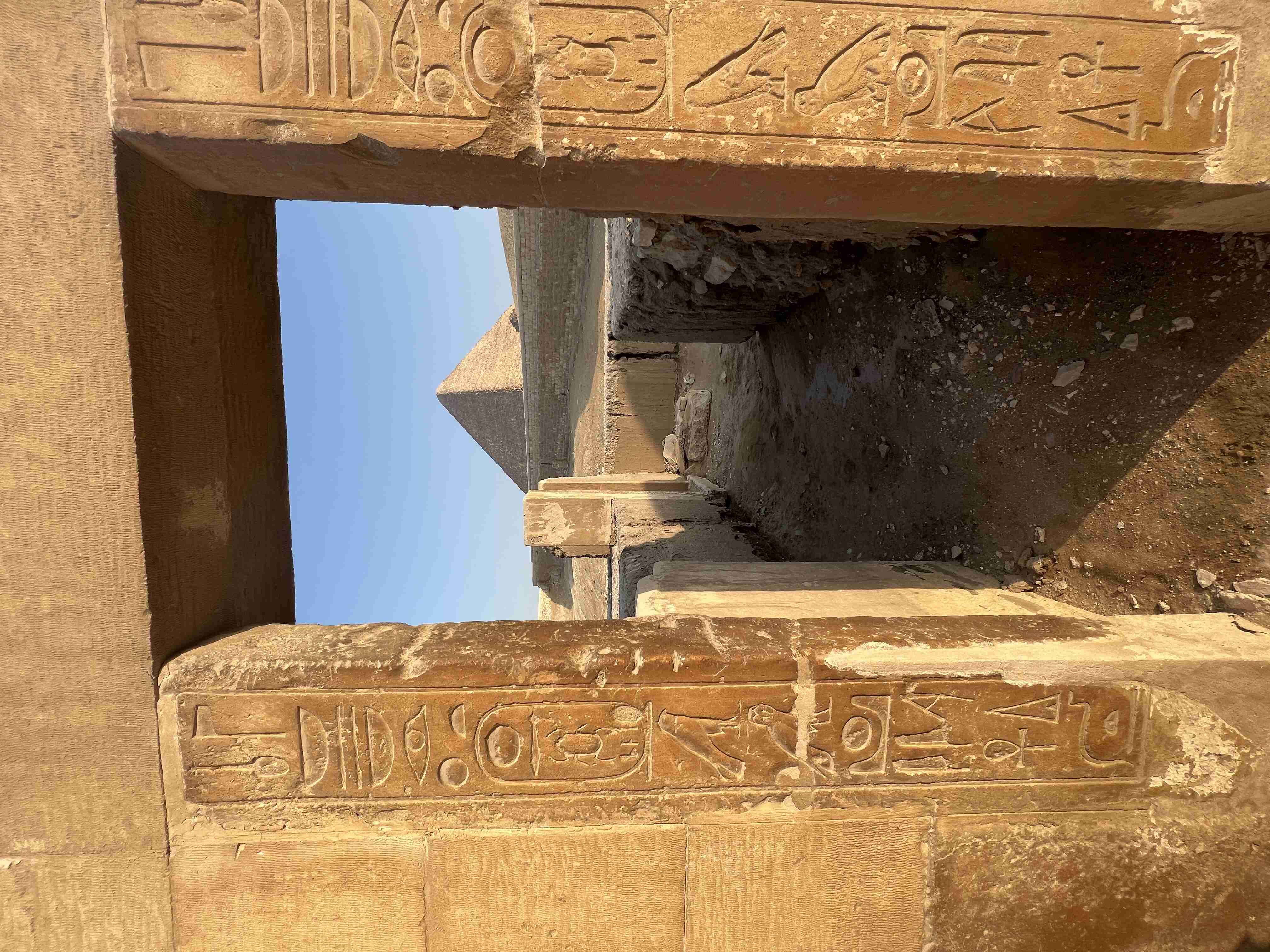 Une ancienne porte en pierre ornée de hiéroglyphes sculptés au complexe de la pyramide à degrés de Saqqara