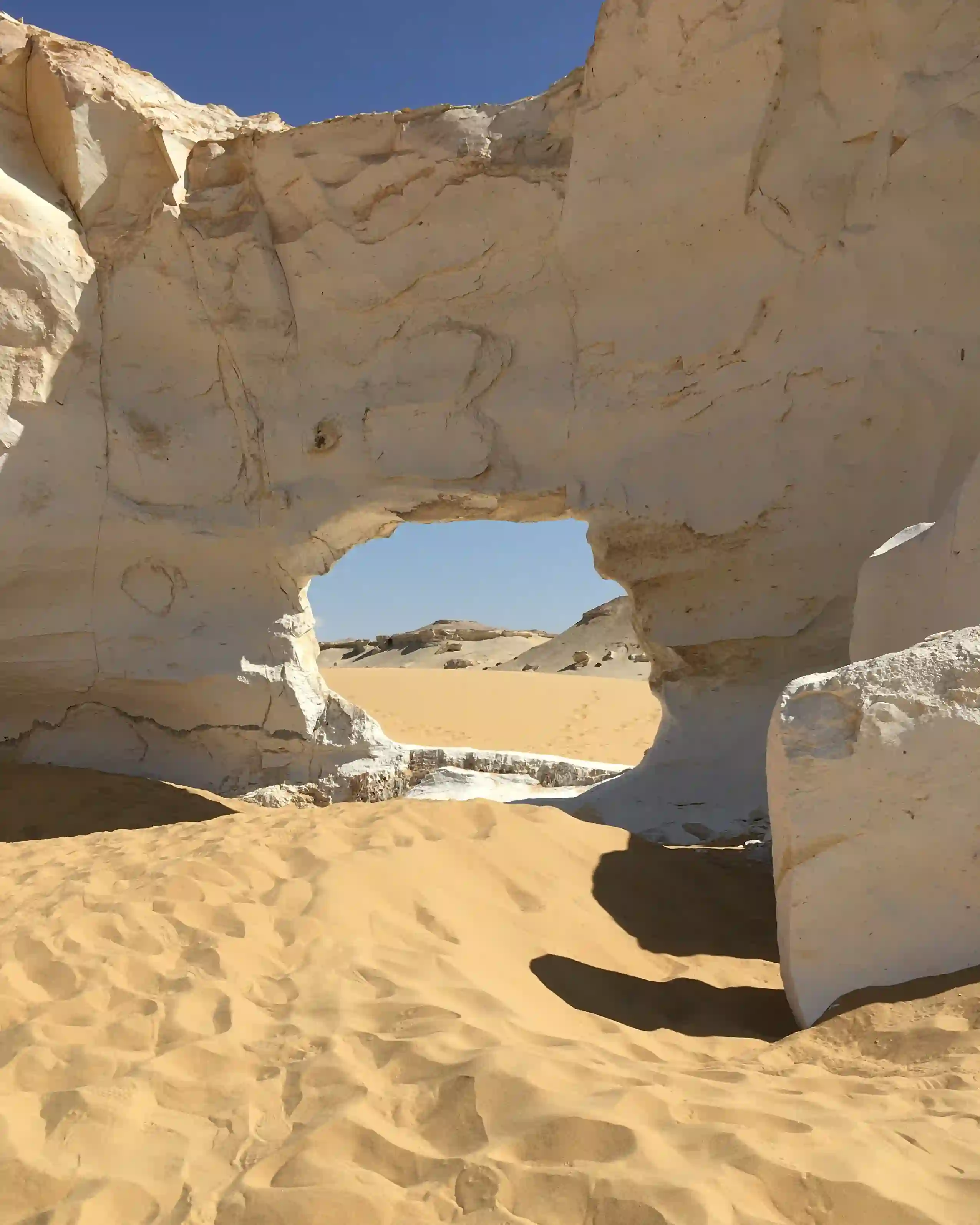A natural chalk rock archway forming a scenic window over the surreal landscapes of White Desert in Egypt