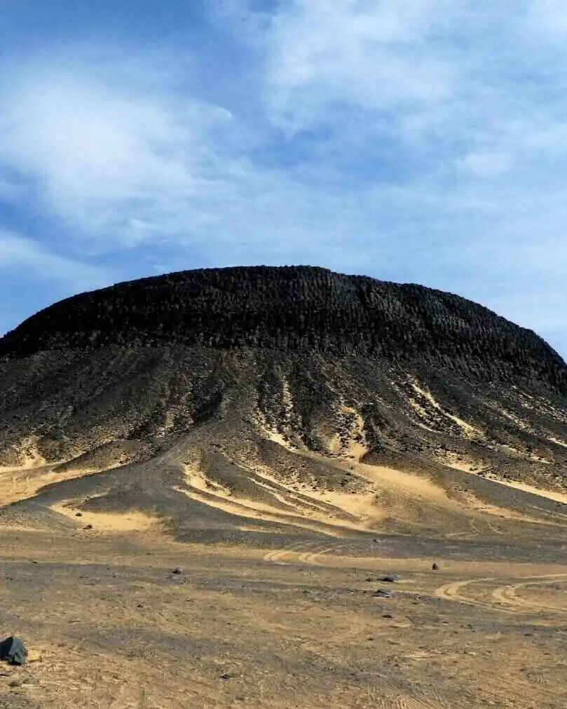 Al-Marsous Mountain, a famous extinct volcanic cone located within the surreal Black Desert of Egypt